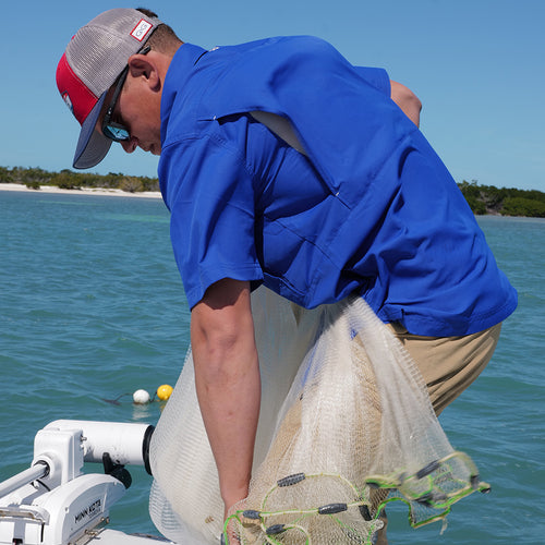 man fishing wearing gameguard hydroblue shirt on boat wearing GameGuard cap showing back vents
