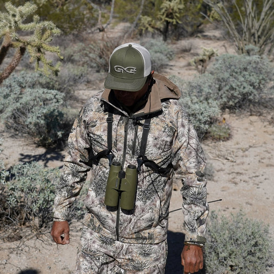 man walking wearing gameguard guia grande jacket and pants with olive cap and stone meshback