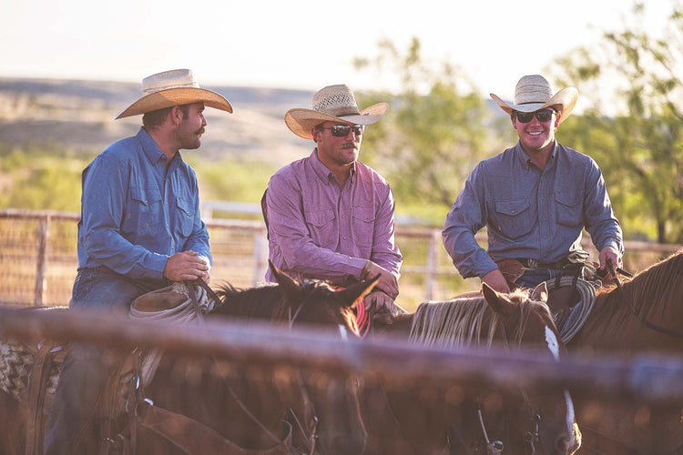 three men riding horses wearing cowboy hat in a ranch setting wearing gameguard pearl snaps, one deep water, one crimson, and one caviar