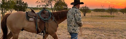 Man walking horse wearing GameGuard Barn Jacket & cowboy hat