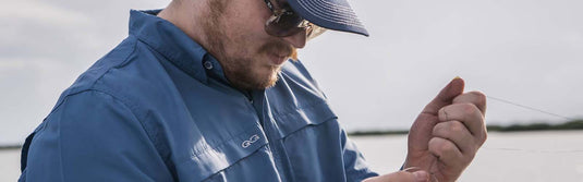 Man wearing GameGuard MicroFiber Shirt and GameGuard hat holding fishing line