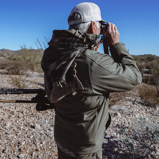 Man using binoculars looking at horizon wearing GameGuard Agave Guia Grande Jacket