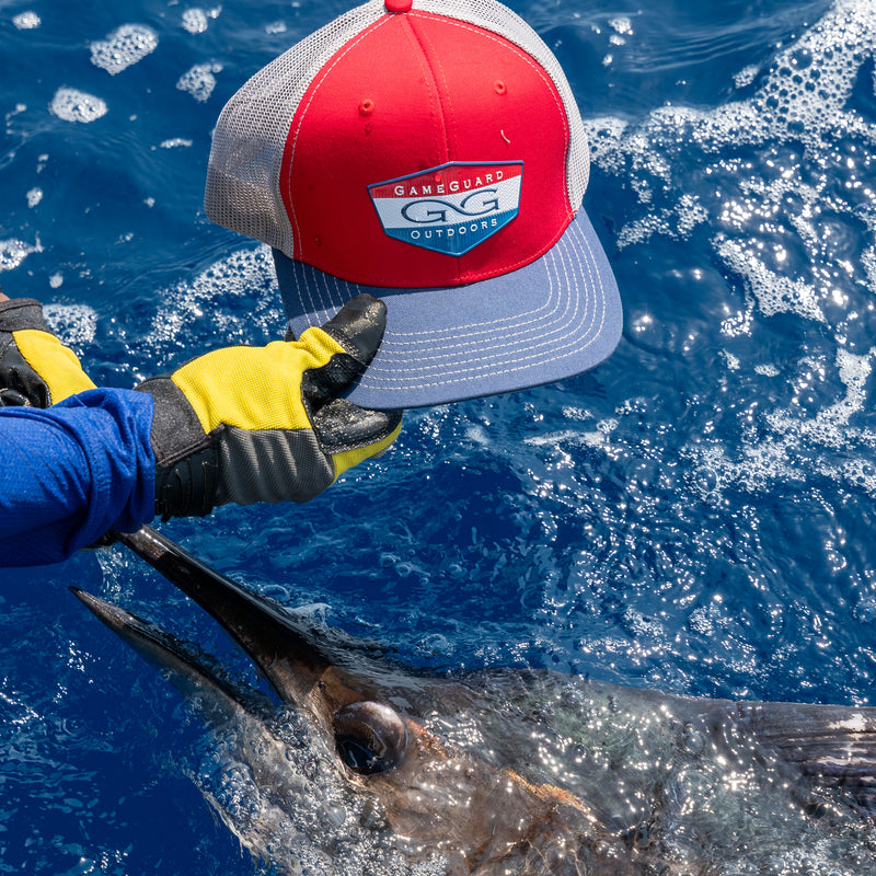 Load image into Gallery viewer, man holding red tricolor cap with glacier meshback over blue water and a marlin
