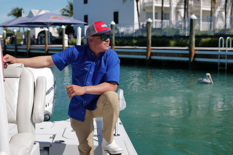 Man Standing on boat wearing GameGuard Classic Fit HydroBlue Shirt and GameGuard cap