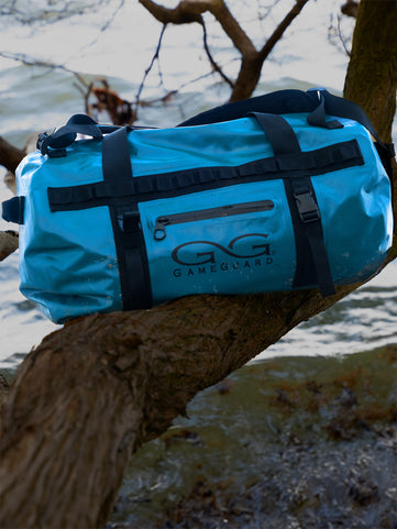 GameGuard Marine DryDuffle sitting on a tree branch over water in the outdoors