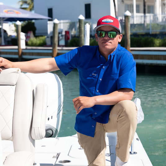 Man standing on boat wearing GameGuard HydroBlue Classic Fit MicroFiber Shirt and GameGuard cap