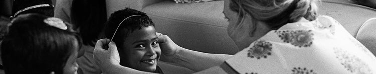 woman placing headband on young girl smiling at camera